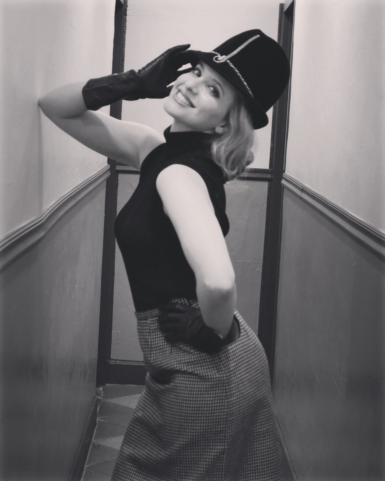 Black and white portrait in a hat and gloves in a hallway