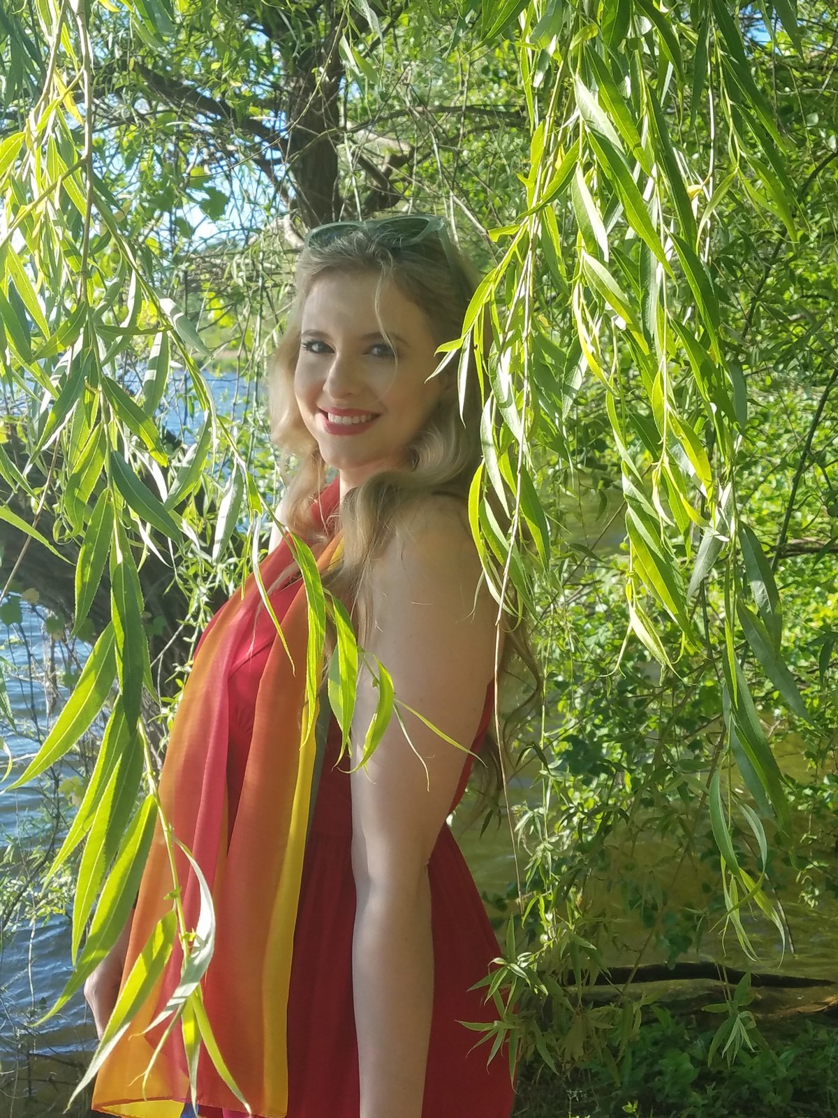 Jenilyn in a red dress beneath willow branches by the water